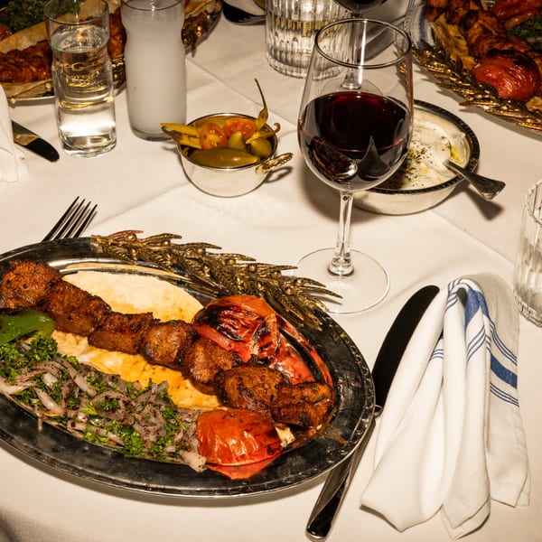 Mediterranean shish kebab with grilled tomatoes, onions, and parsley, served with red wine and raki.
